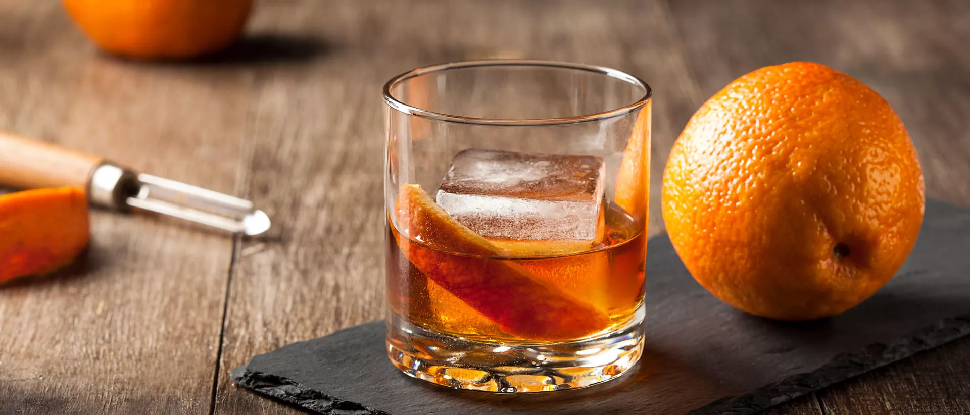 Lifestyle Image of Old Fashioned Cocktail garnished with orange peel and ice