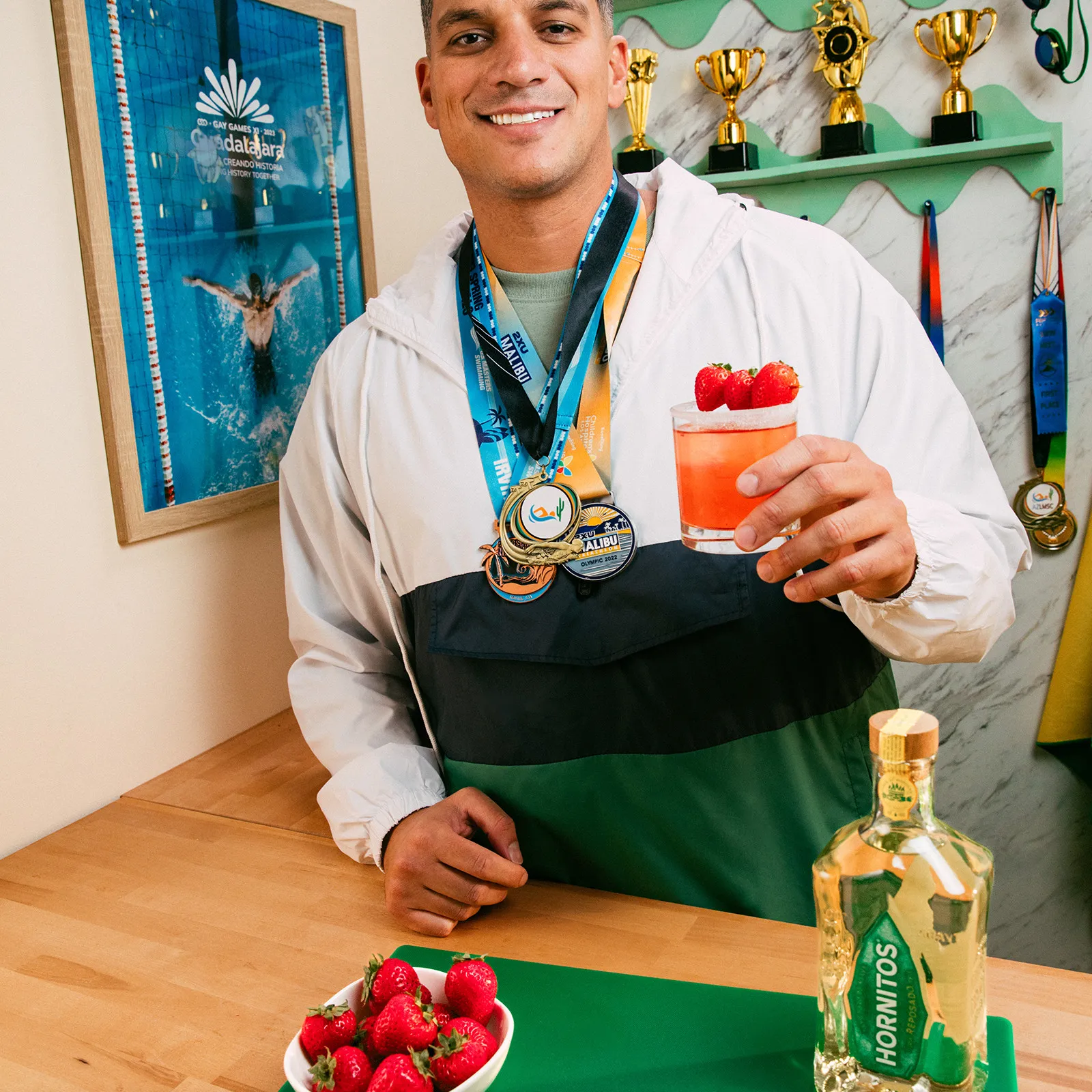 A man holding a drink, possibly a cocktail, with a relaxed expression on his face.