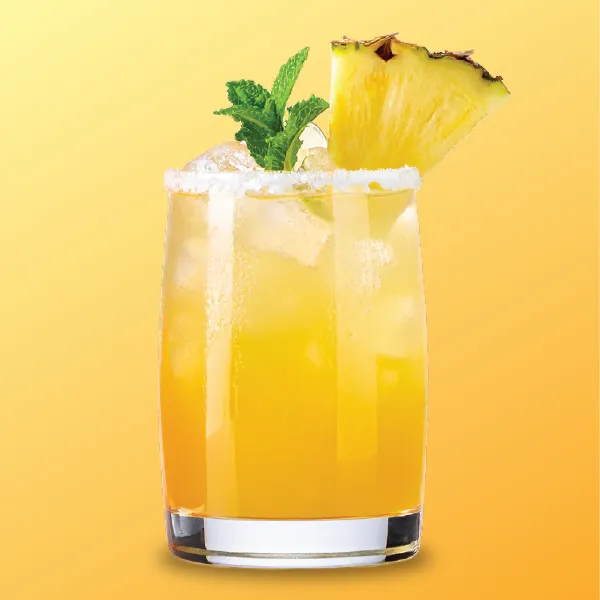 A refreshing yellow cocktail garnished with mint and a pineapple slice, served in a glass filled with ice against a vibrant orange background.
